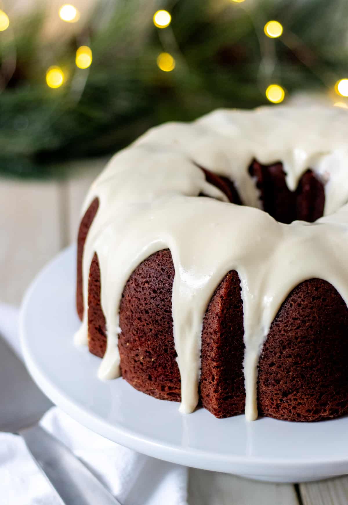 Red velvet bundt cake with cream cheese frosting on a cake plate.