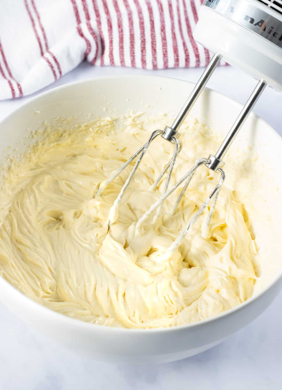 Cheesecake filling in a bowl with mixers.