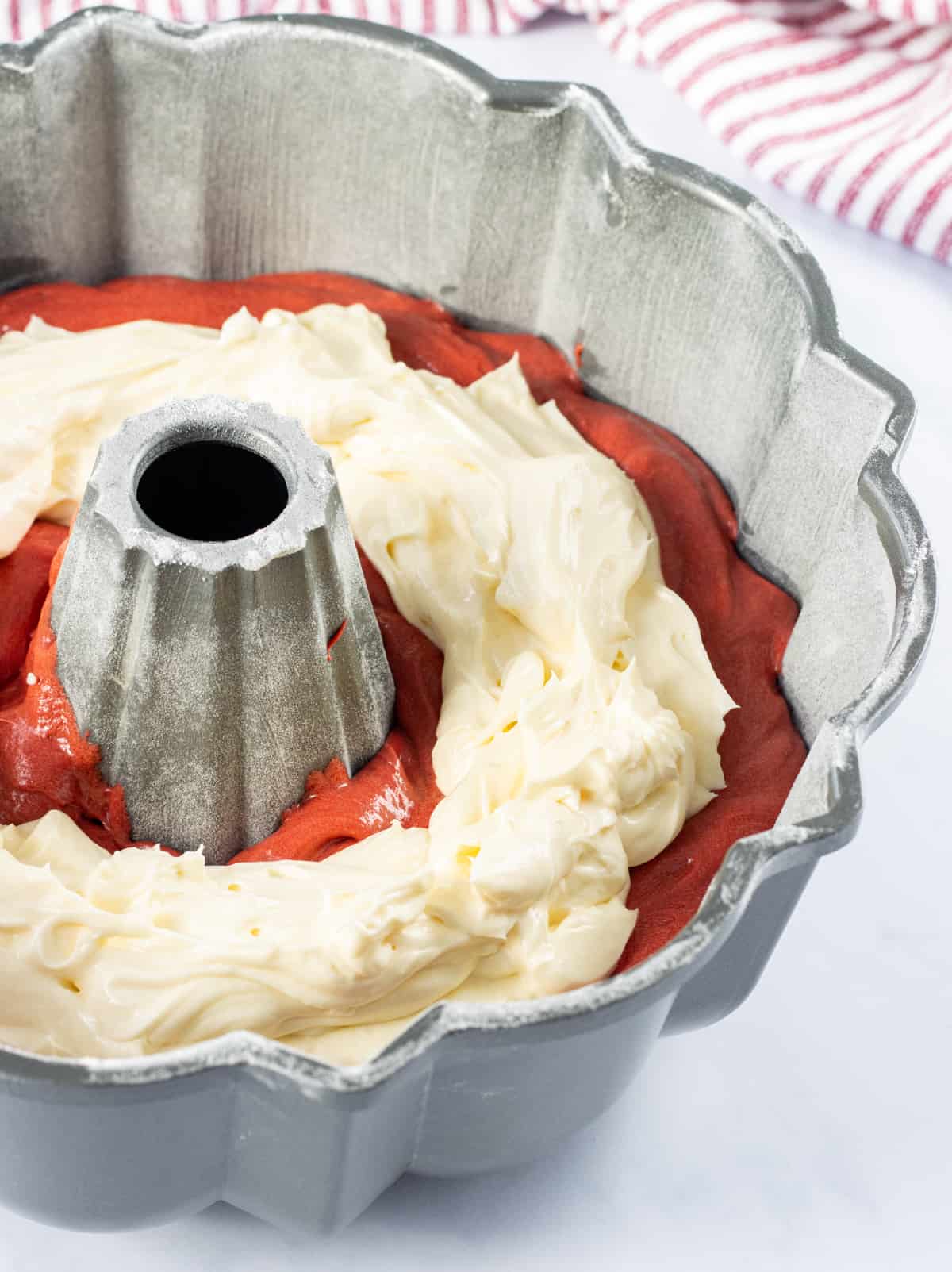 Bundt pan with a layer of red velvet batter and the cheesecake filling on top.