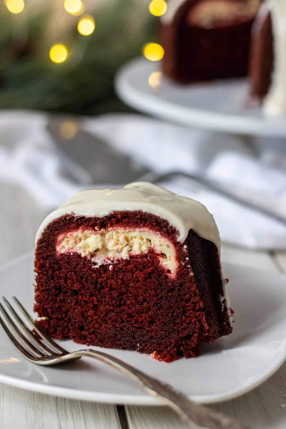 Slice of cheesecake filled red velvet bundt cake on a plate with a fork.