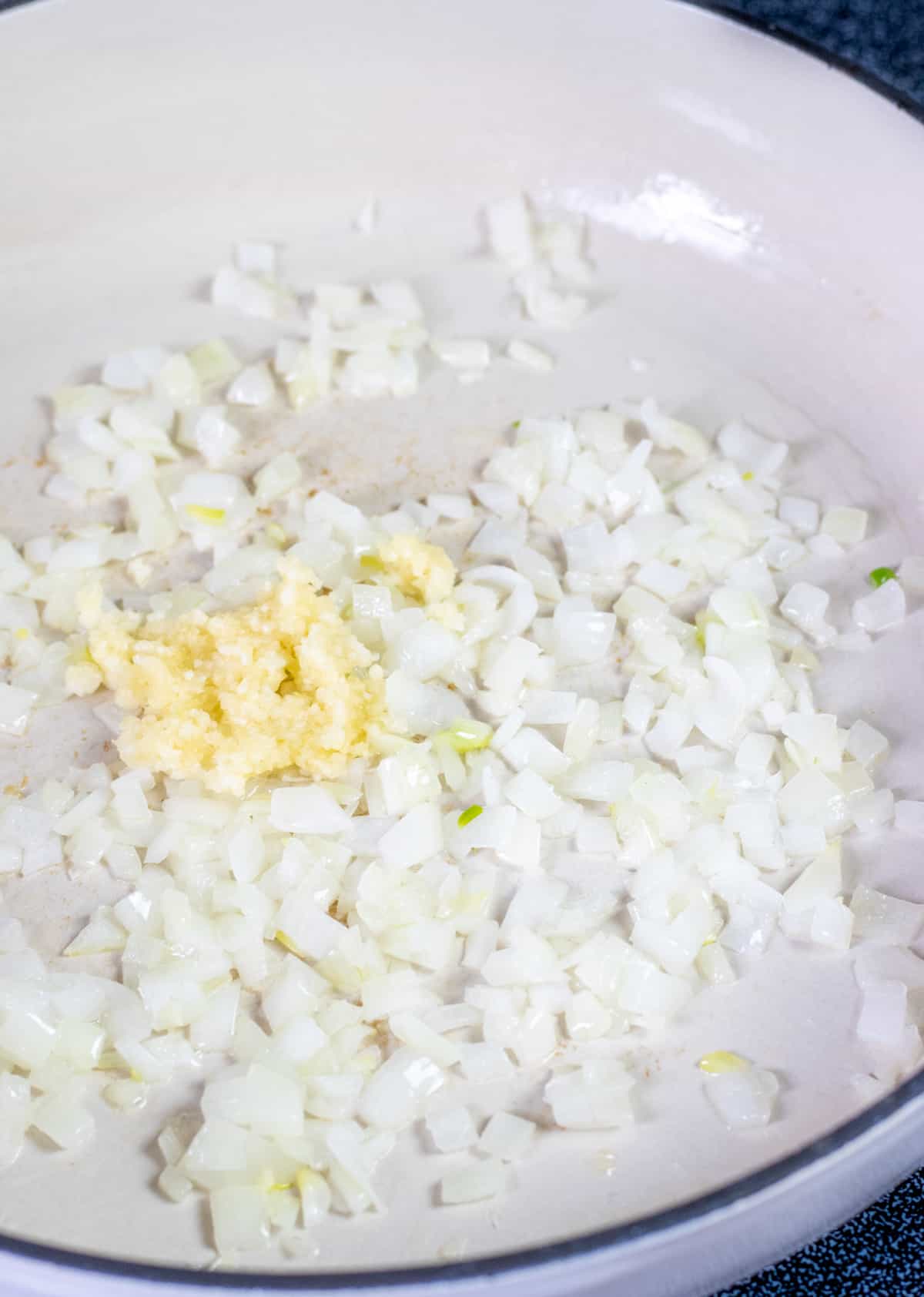 Diced onion and garlic sautéing in a large casserole dish.