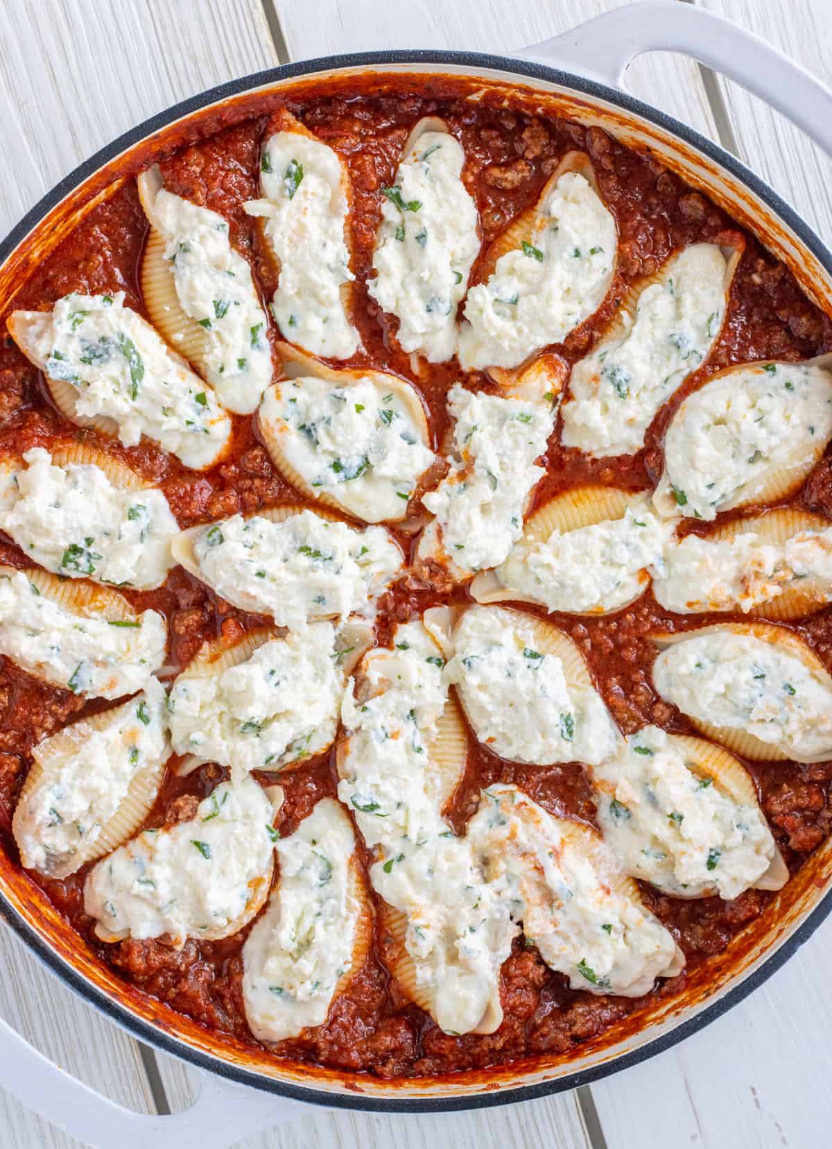 Stuffed pasta shells in a casserole dish with meat sauce.