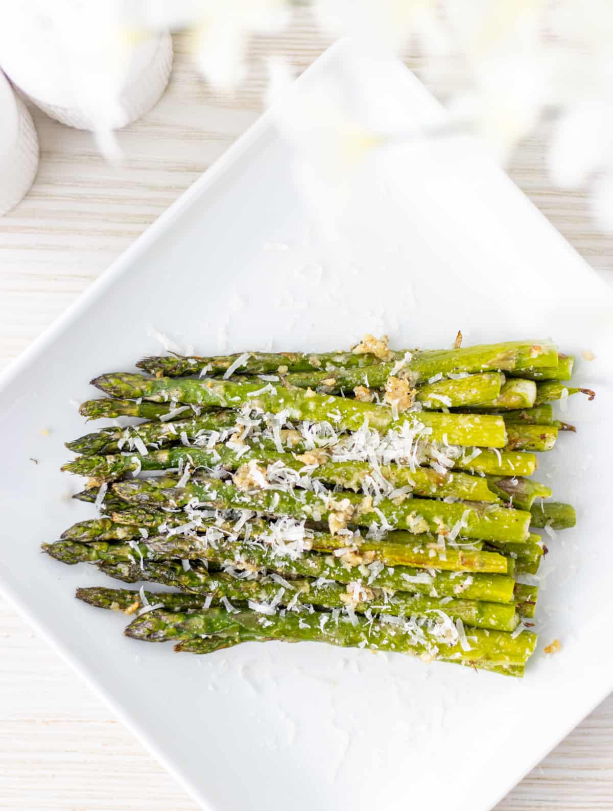 Asparagus on a plate topped with parmesan cheese.