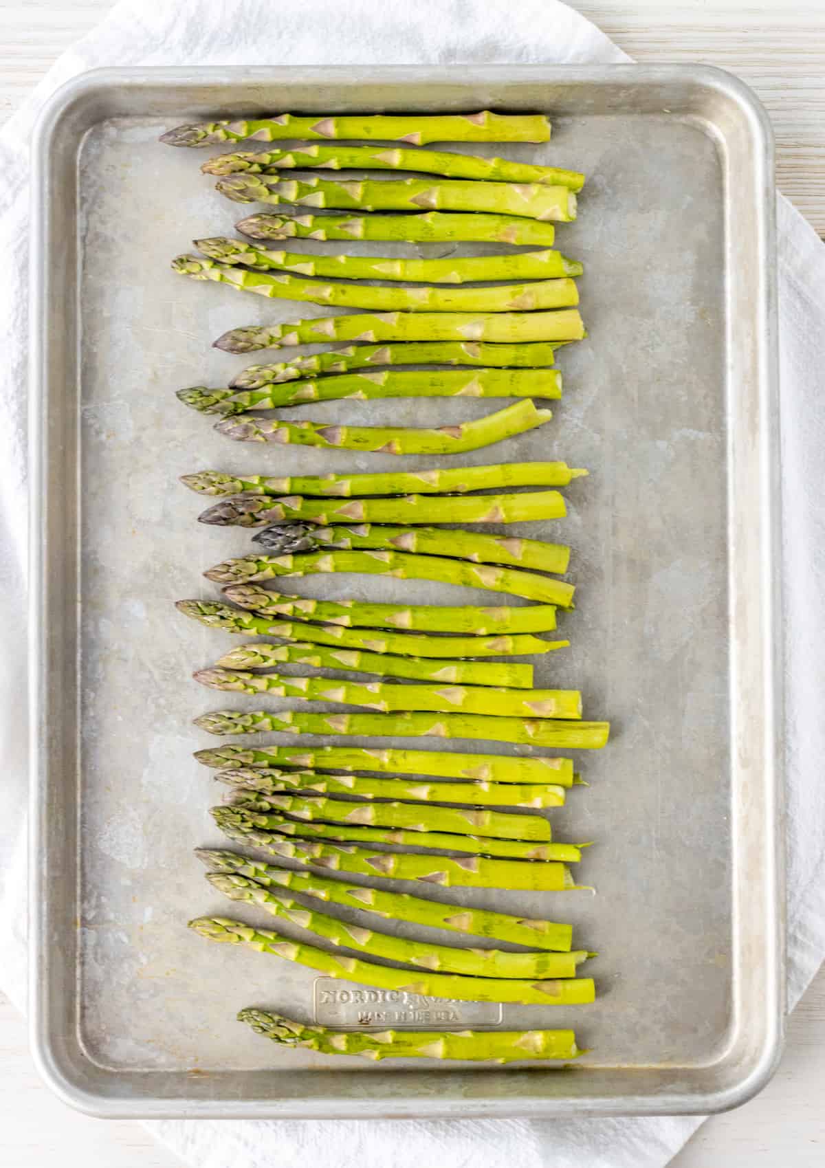 Asparagus on a baking sheet drizzled with olive oil.