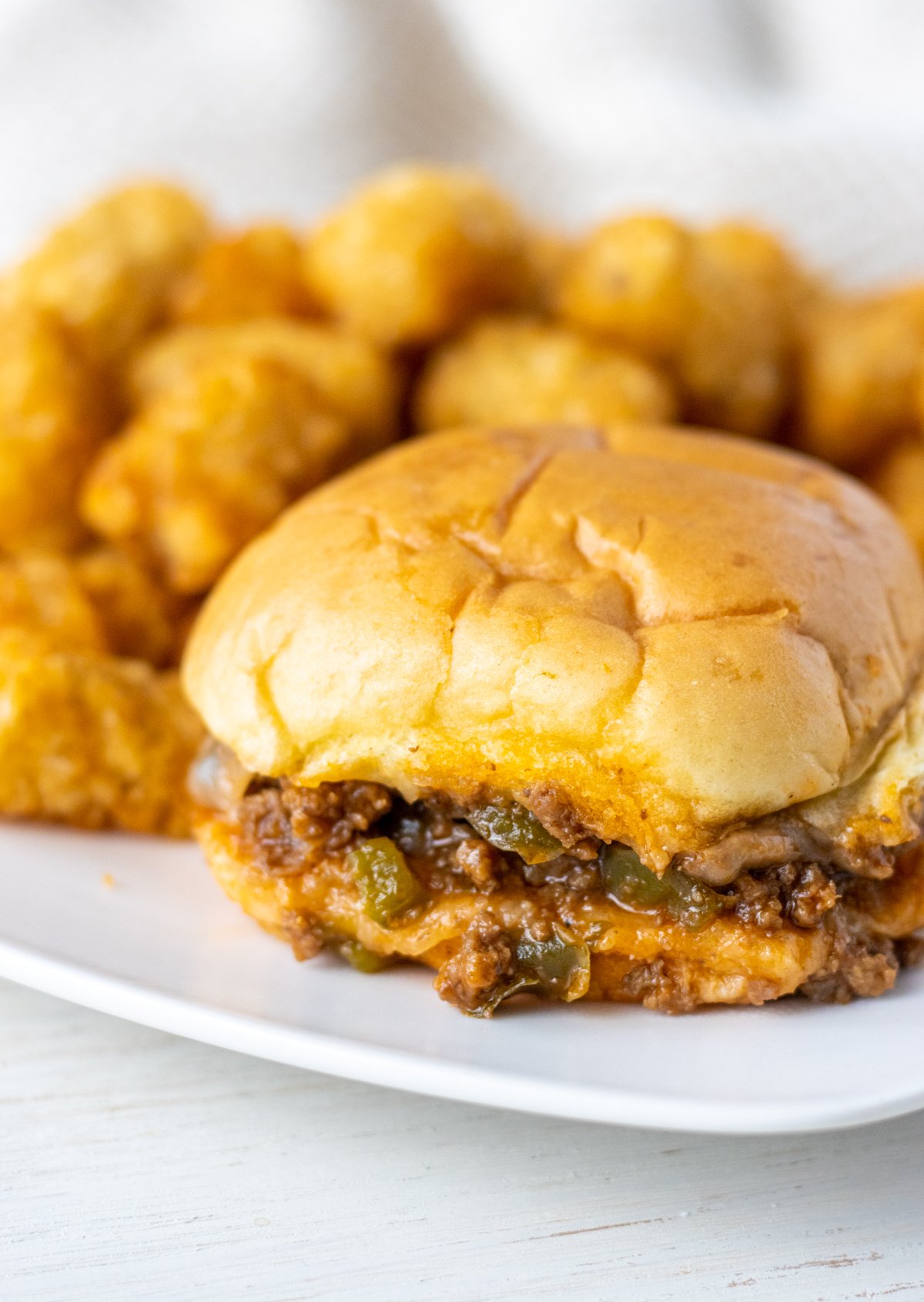 Sloppy joe slider on a plate with tater tots.
