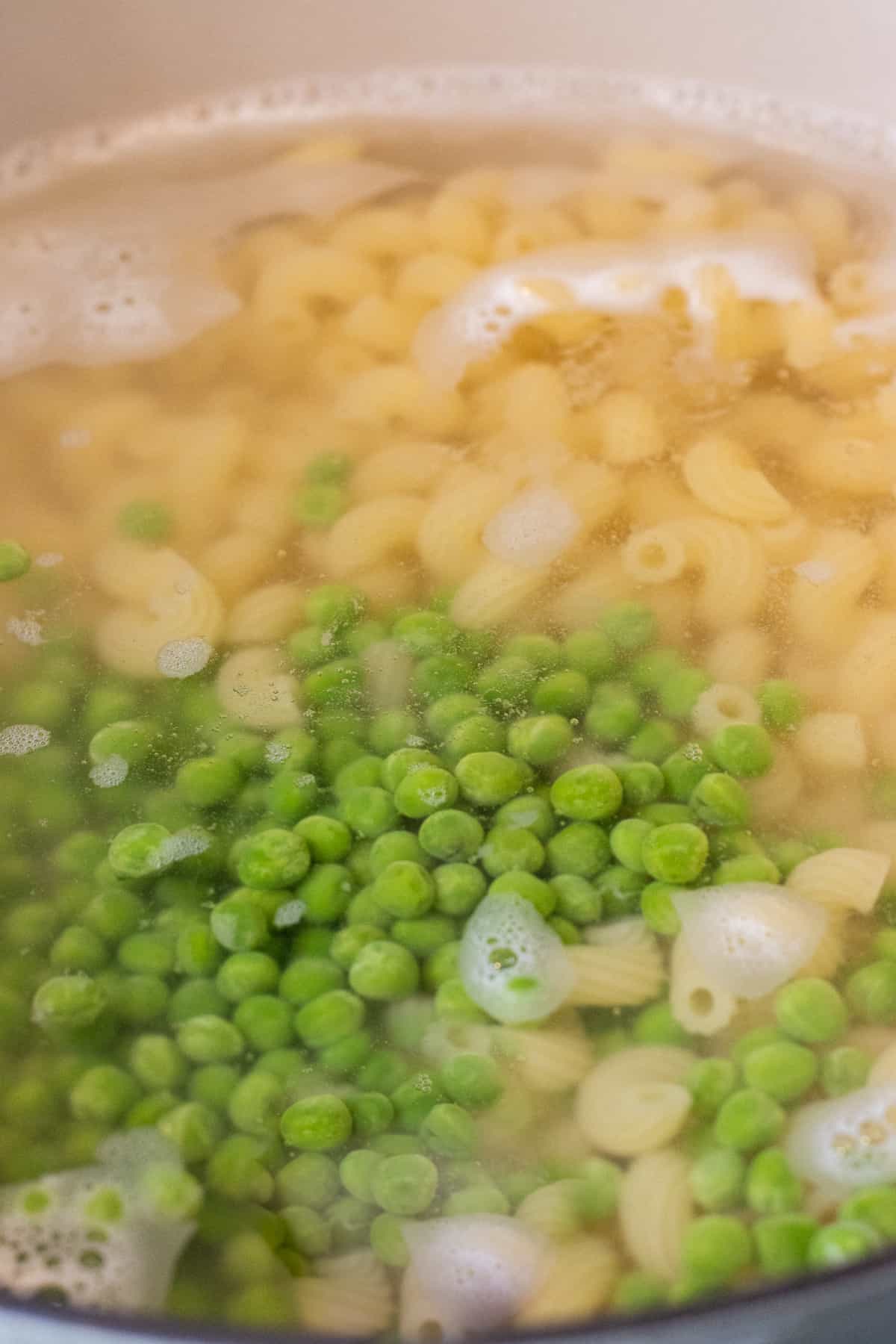 Peas and pasta in a pot with boiling water.