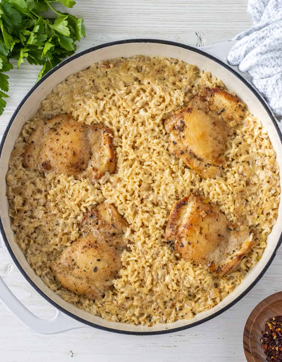 Four browned chicken thighs nestled into rice in a casserole dish.