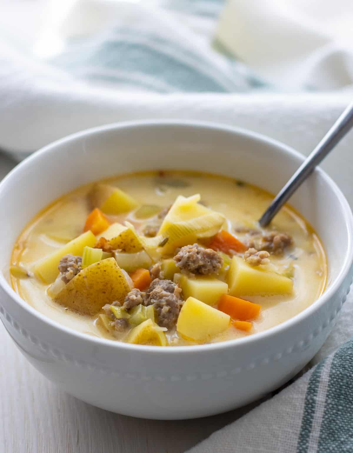 Bowl of sausage and potato soup with a spoon in it.