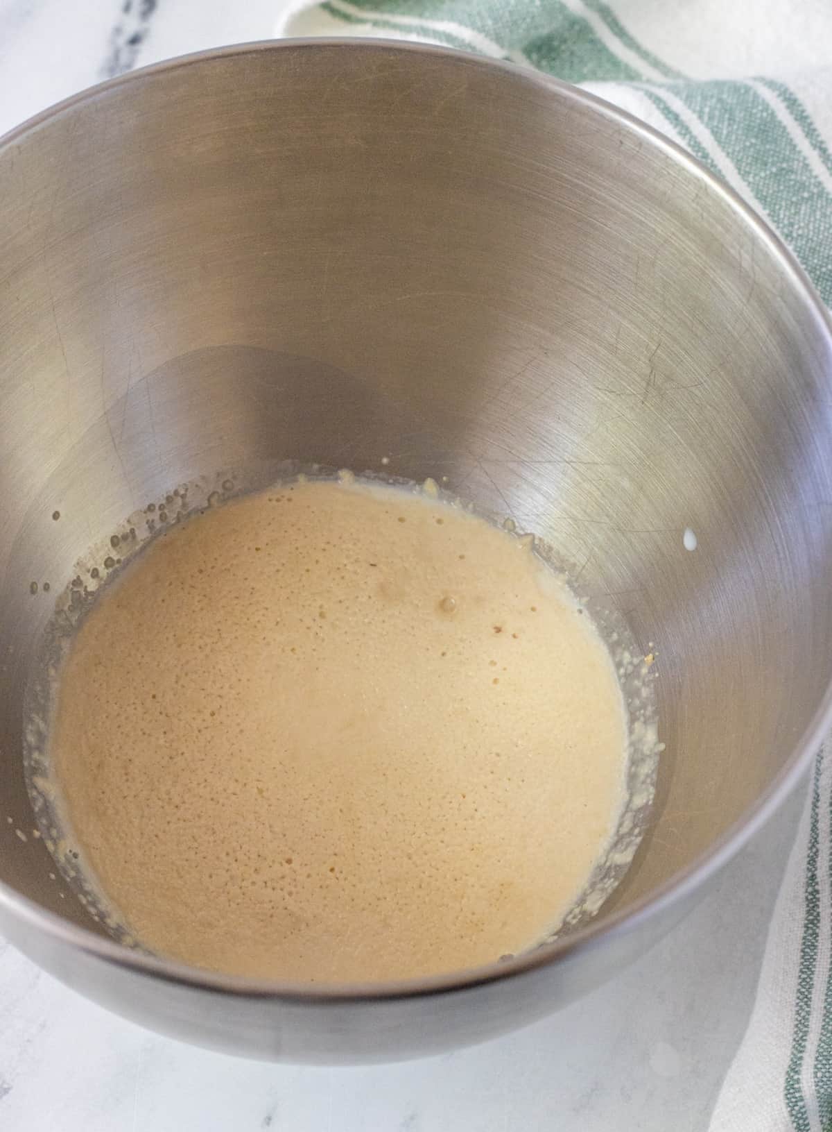 Frothy yeast in milk in a metal bowl.