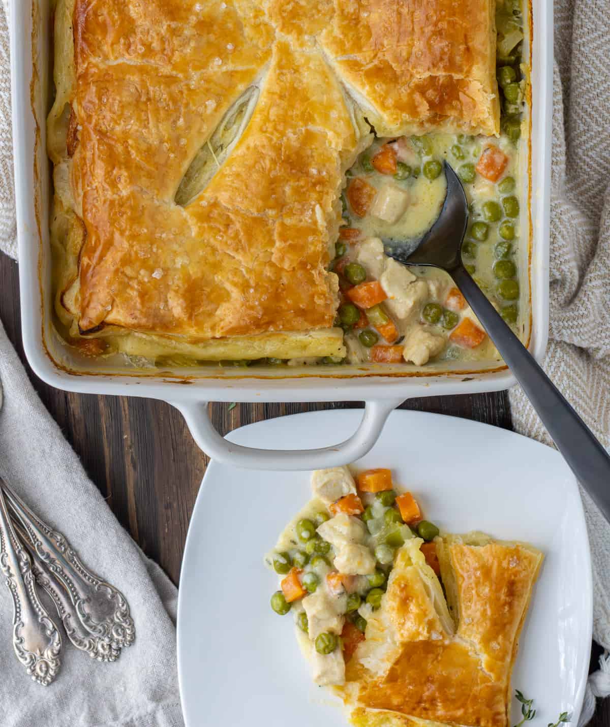 Chicken pot pie in a baking dish with a scoop out on a plate next to it.