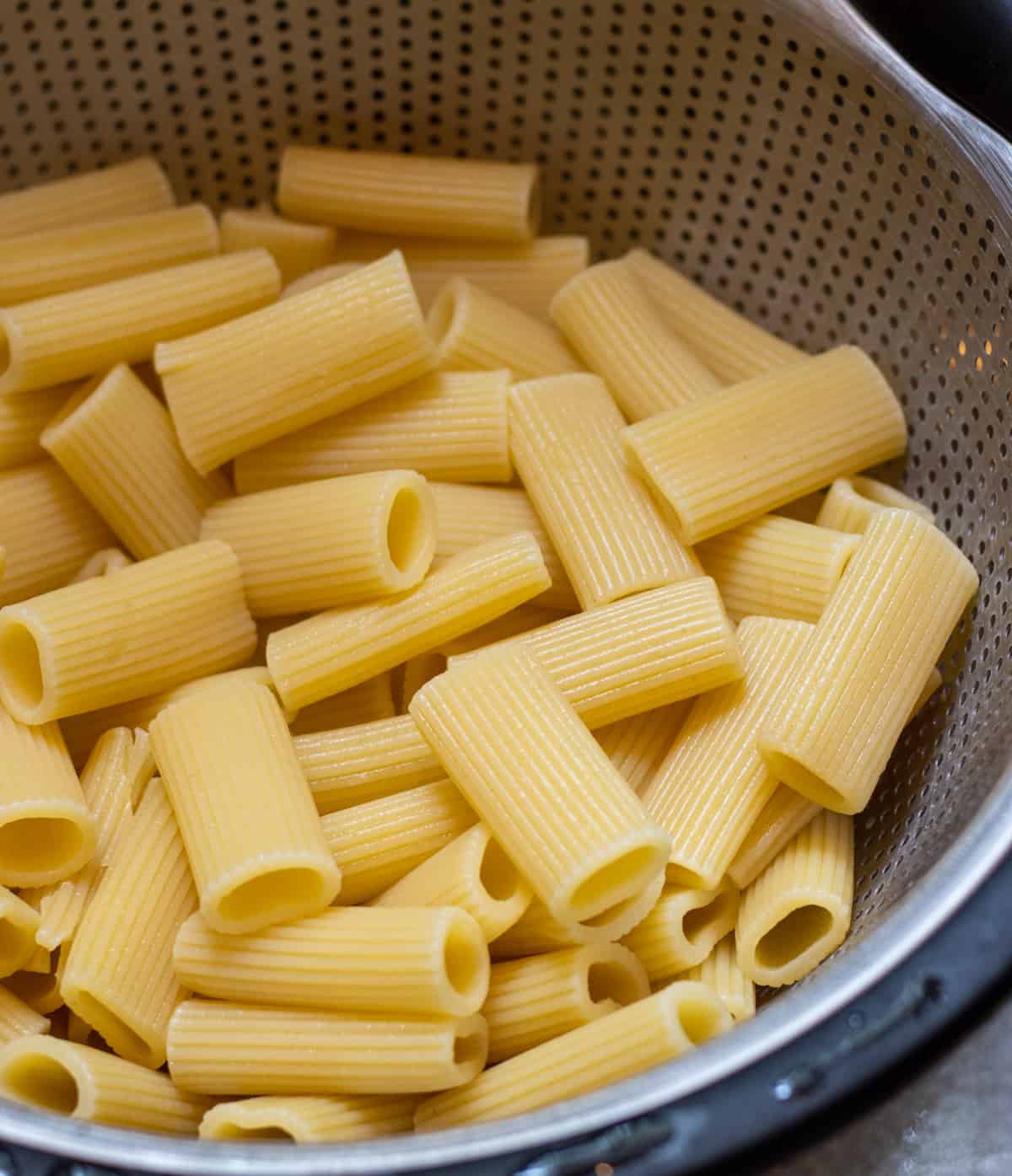 Boiled rigatoni noodles in a colander.