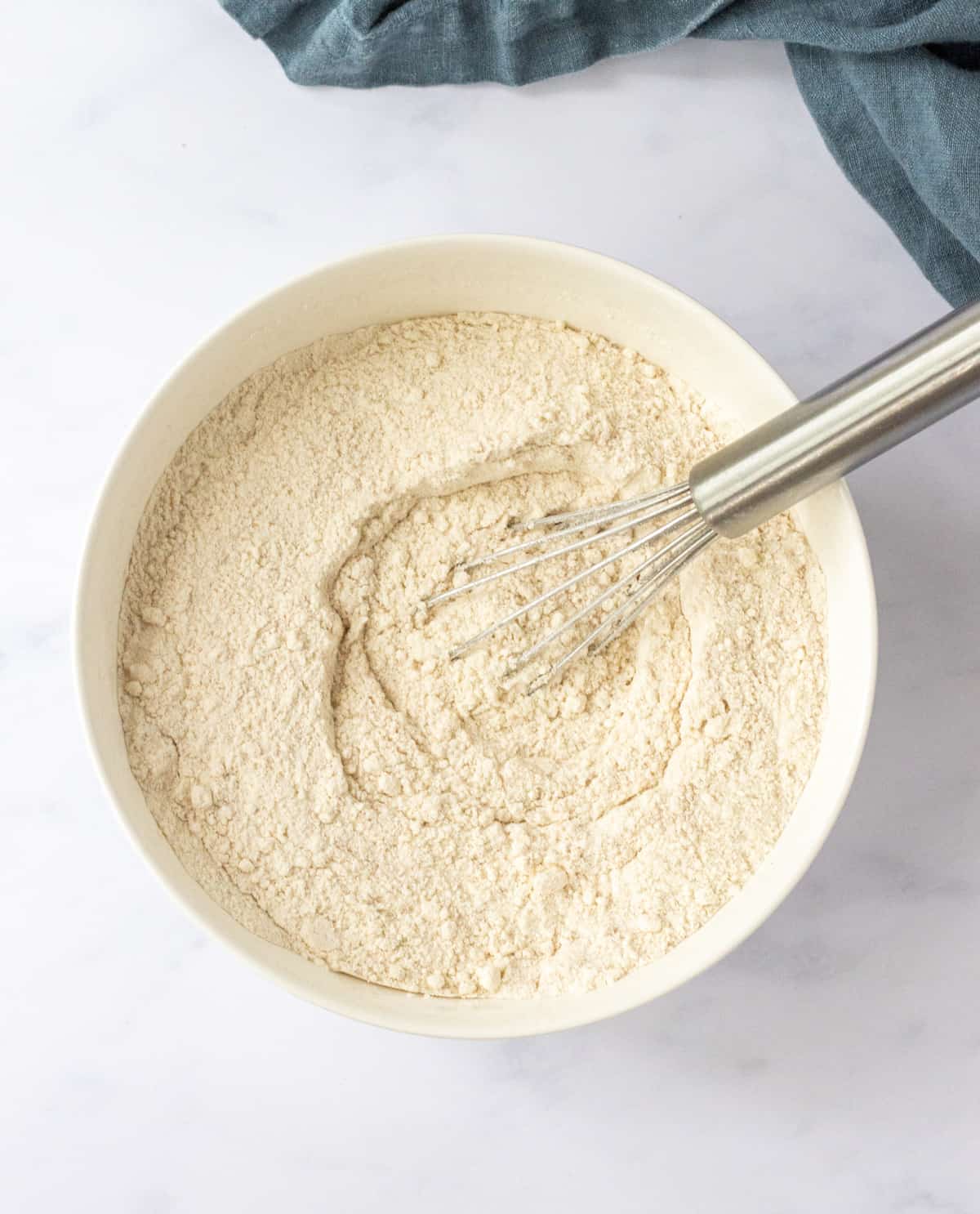Dry ingredients whisked together in a bowl with a whisk.