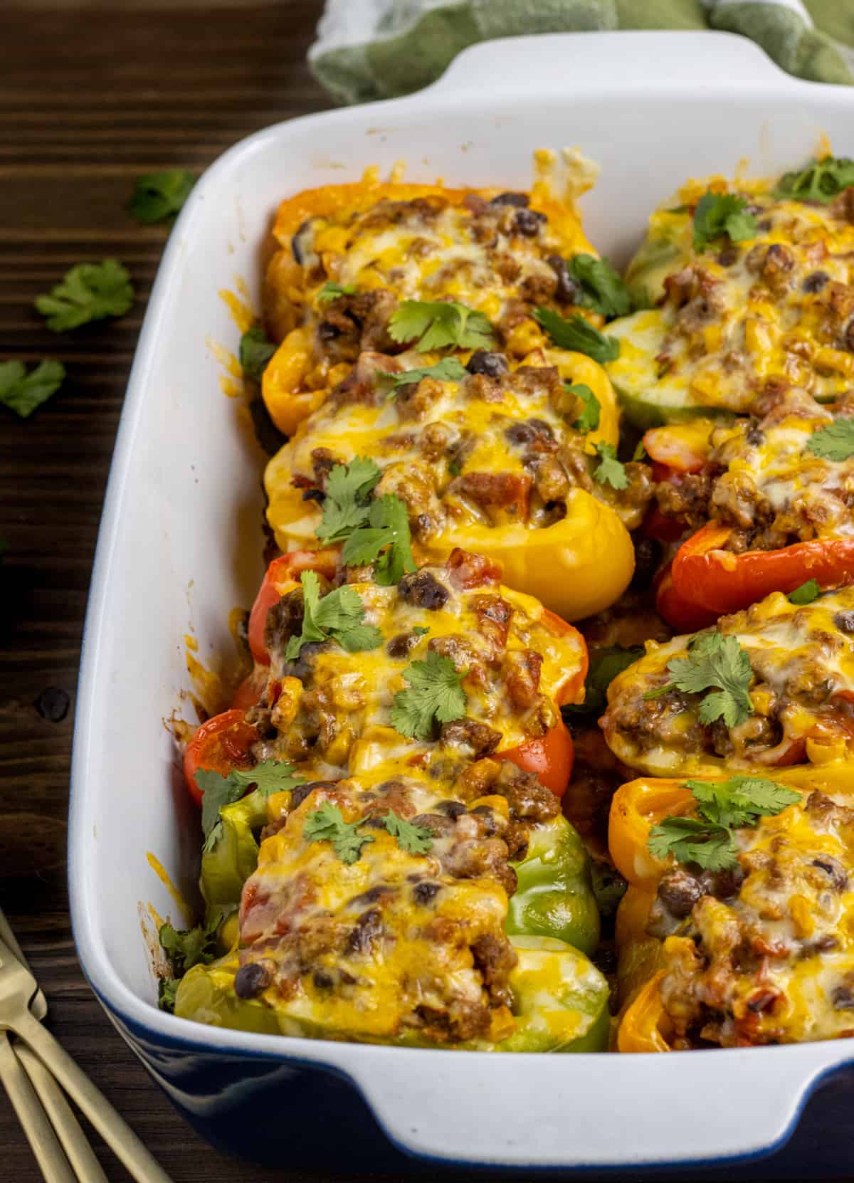 Taco stuffed peppers in a baking dish with forks on the side.