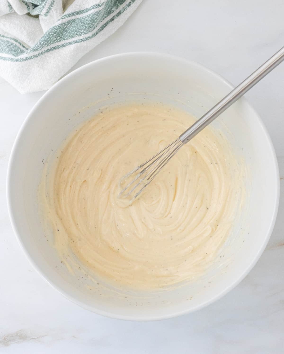 Mayo dressing in a large bowl with a whisk.