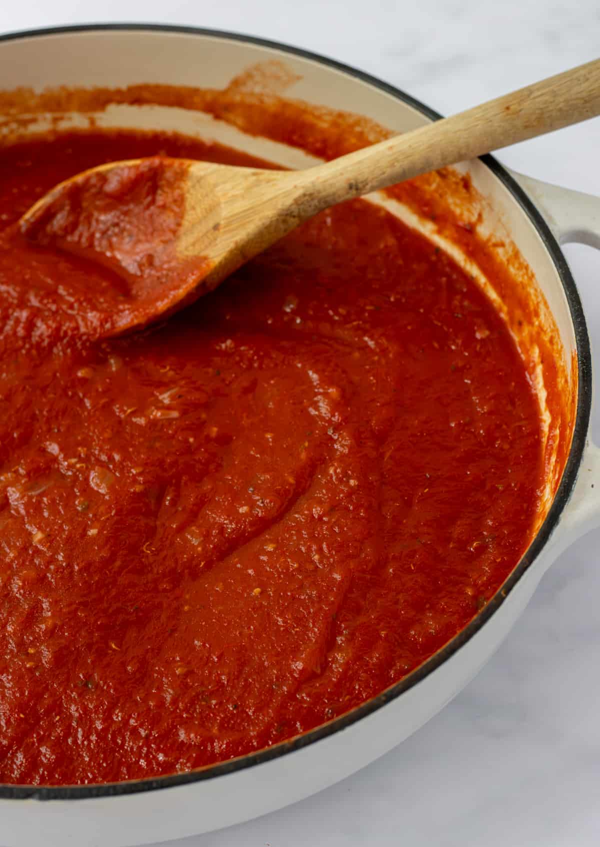 Marinara sauce in a skillet with a wooden spoon.