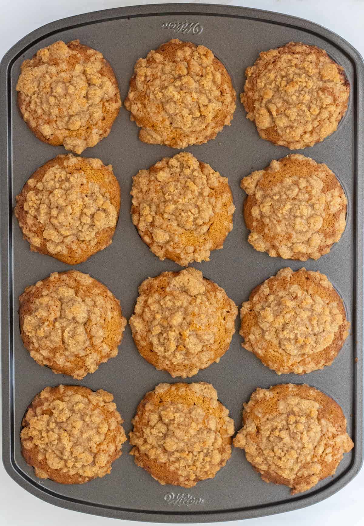Baked cinnamon streusel muffins in a muffin pan.