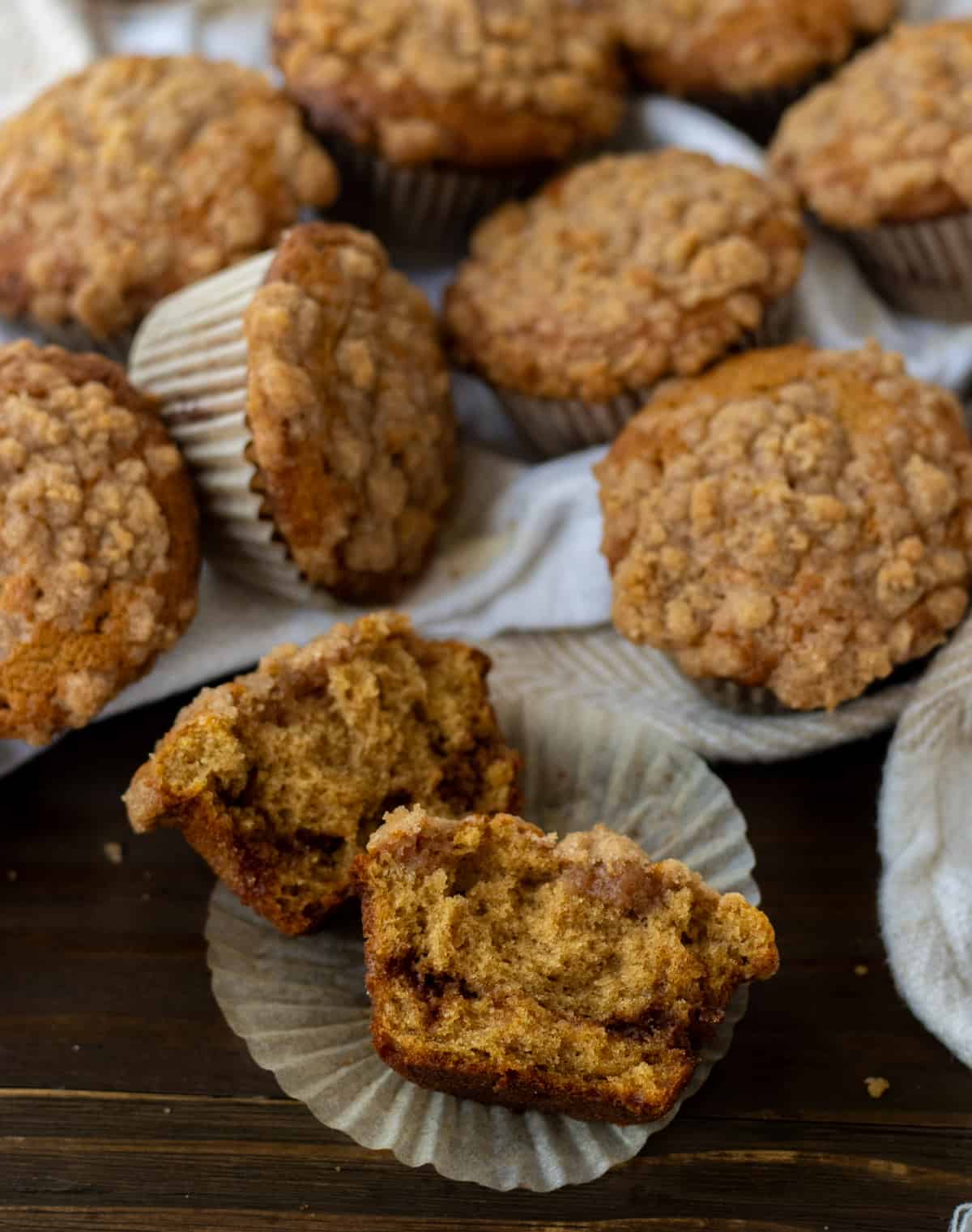 Cinnamon streusel muffins on a towel with one cut open.