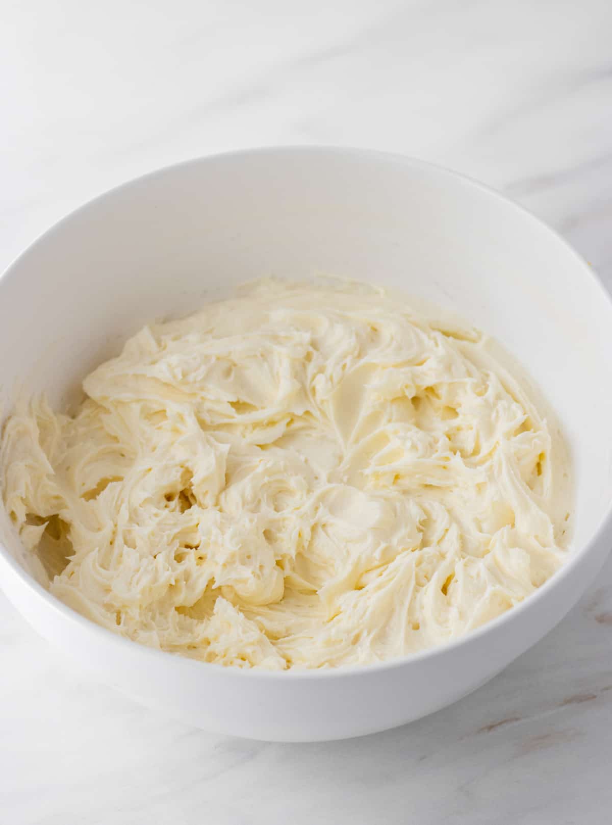 Cream cheese, powdered sugar, vanilla creamed together in a bowl.