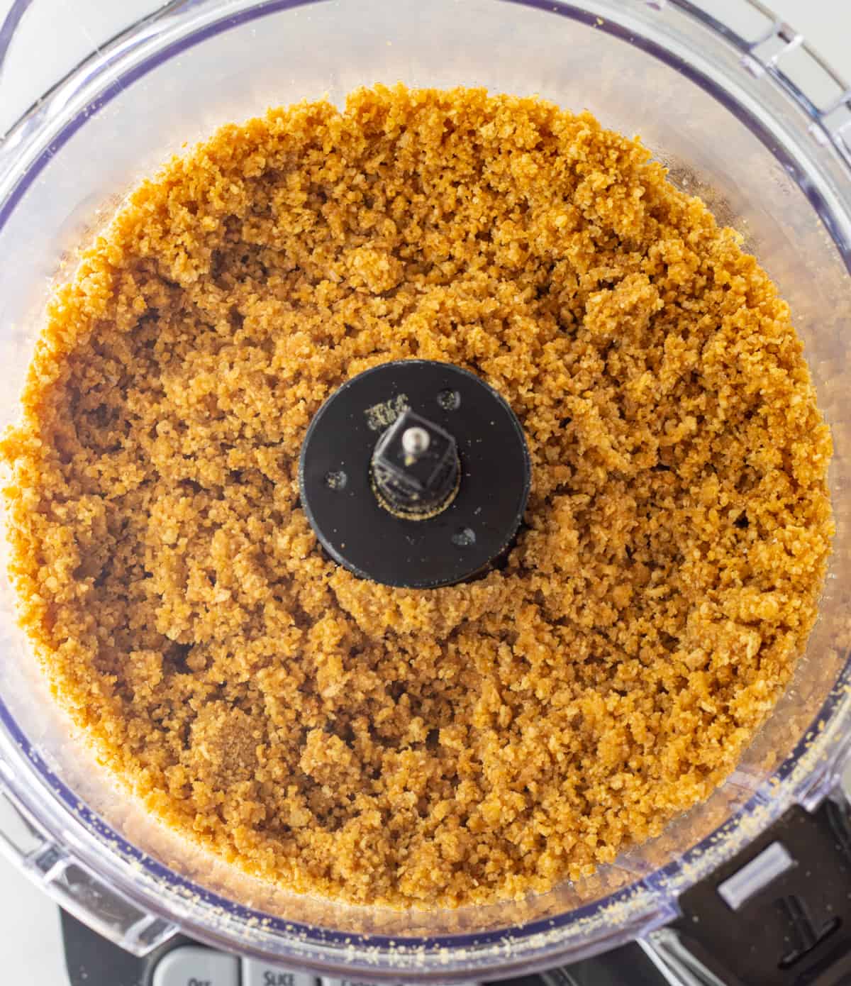 Graham cracker crumbs mixed with melted butter in a food processor.