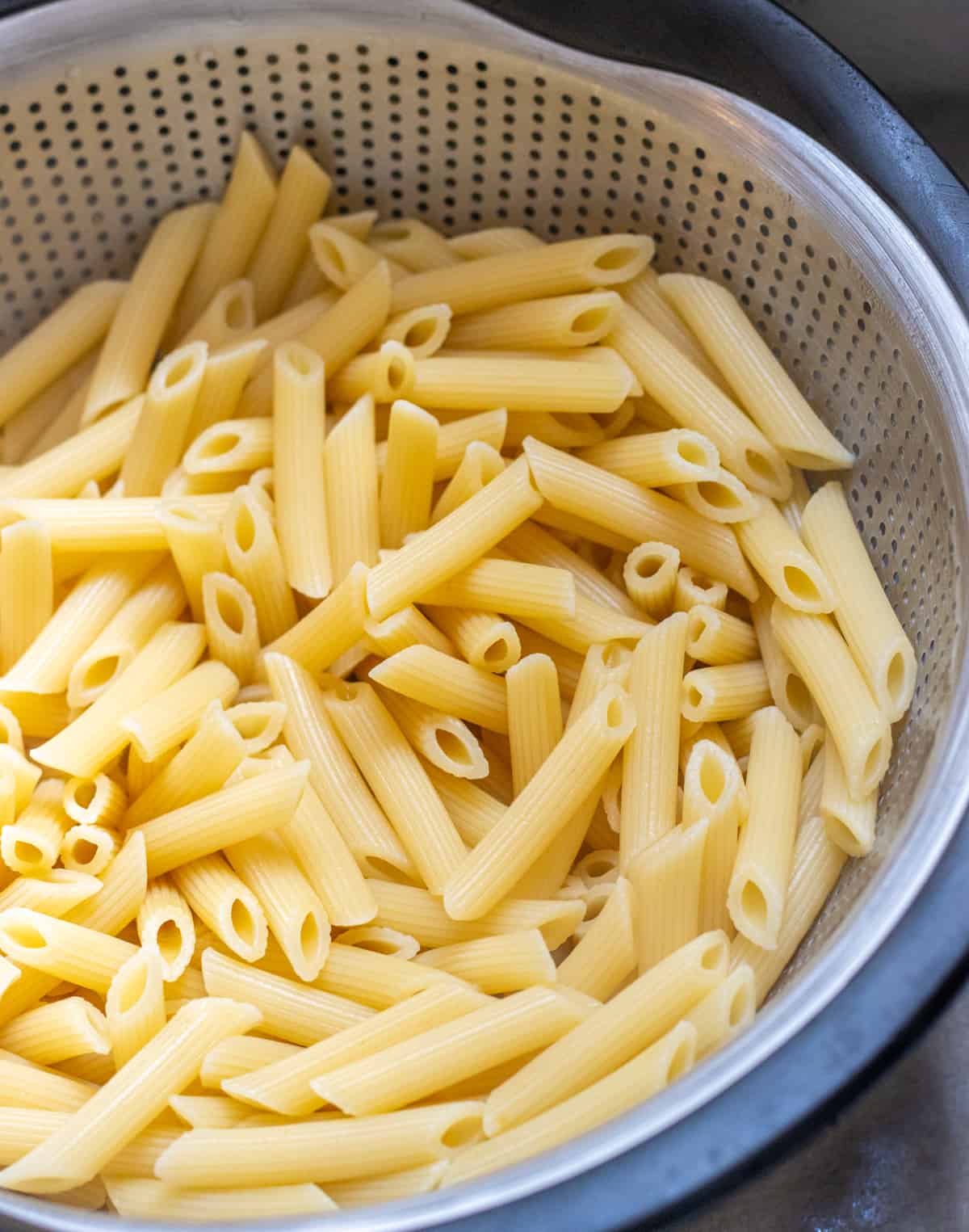 Penne noodles in a colander.