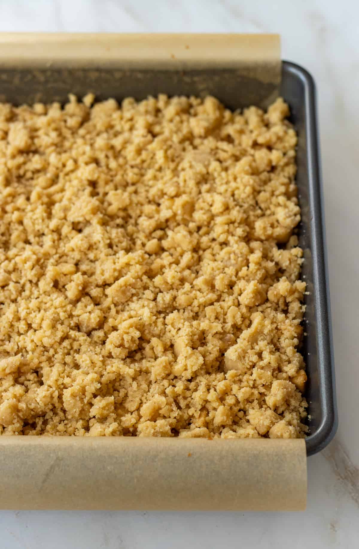 Unbaked apple bars in a parchment lined baking dish.