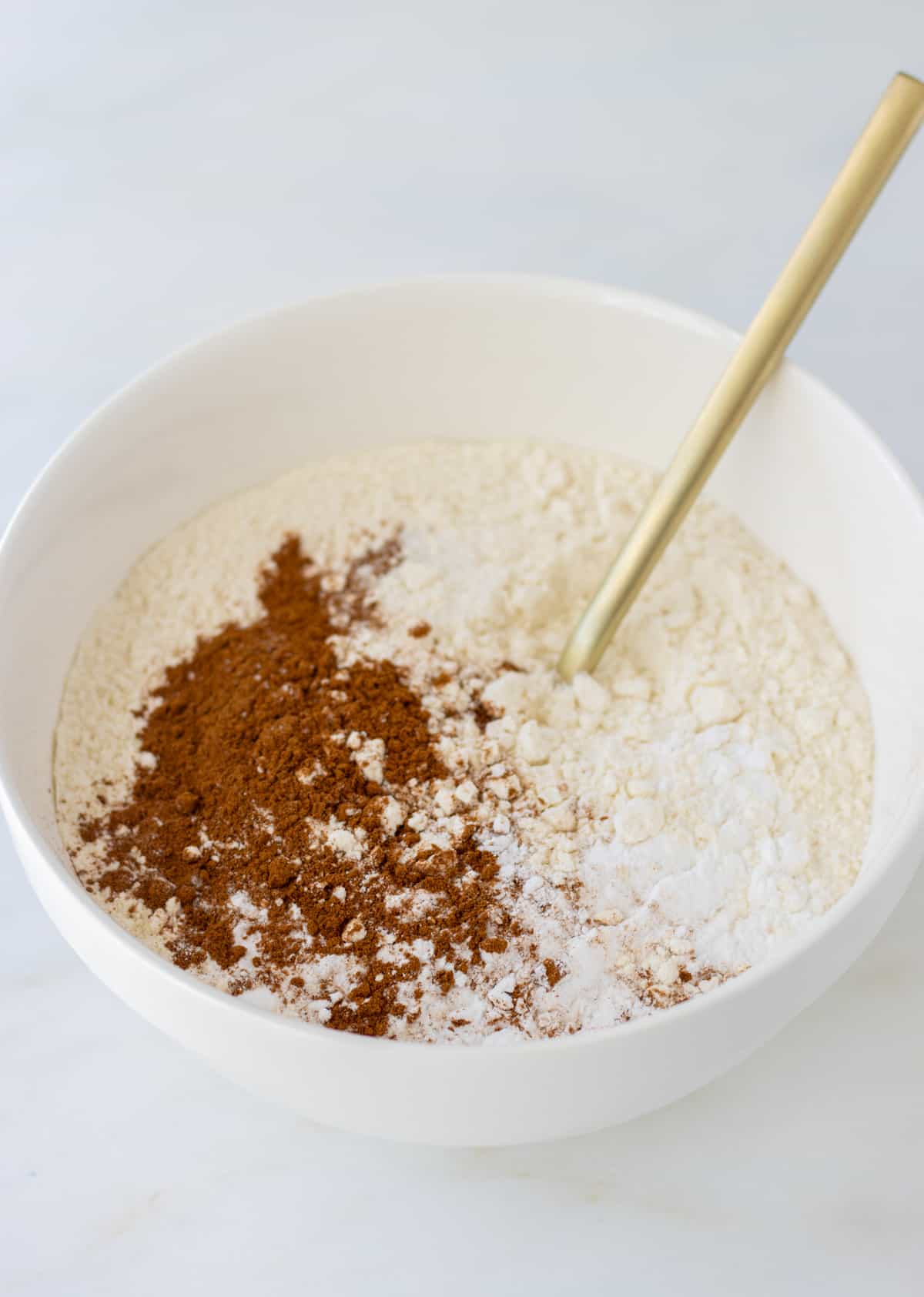 Flour, baking powder, cinnamon, and salt in a bowl with a fork.