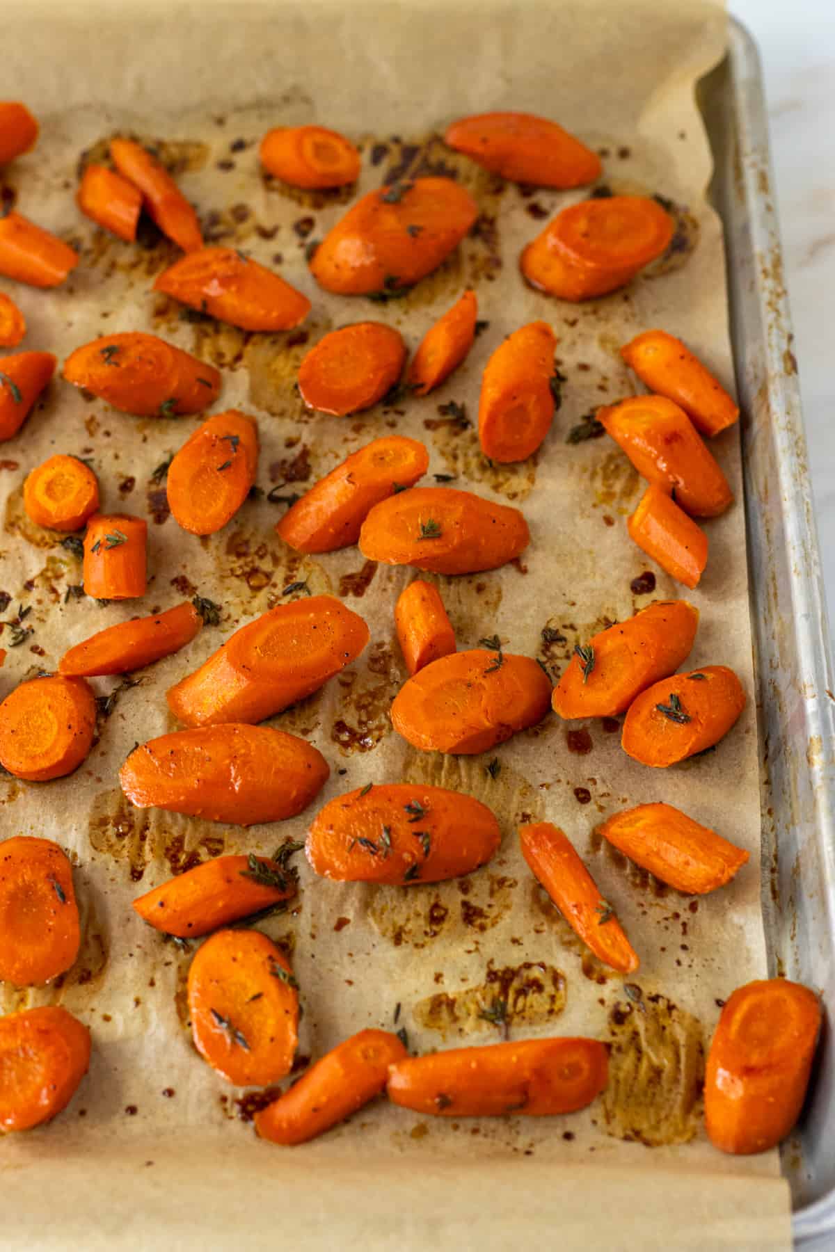 Honey thyme carrots roasted on a parchment lined baking sheet.
