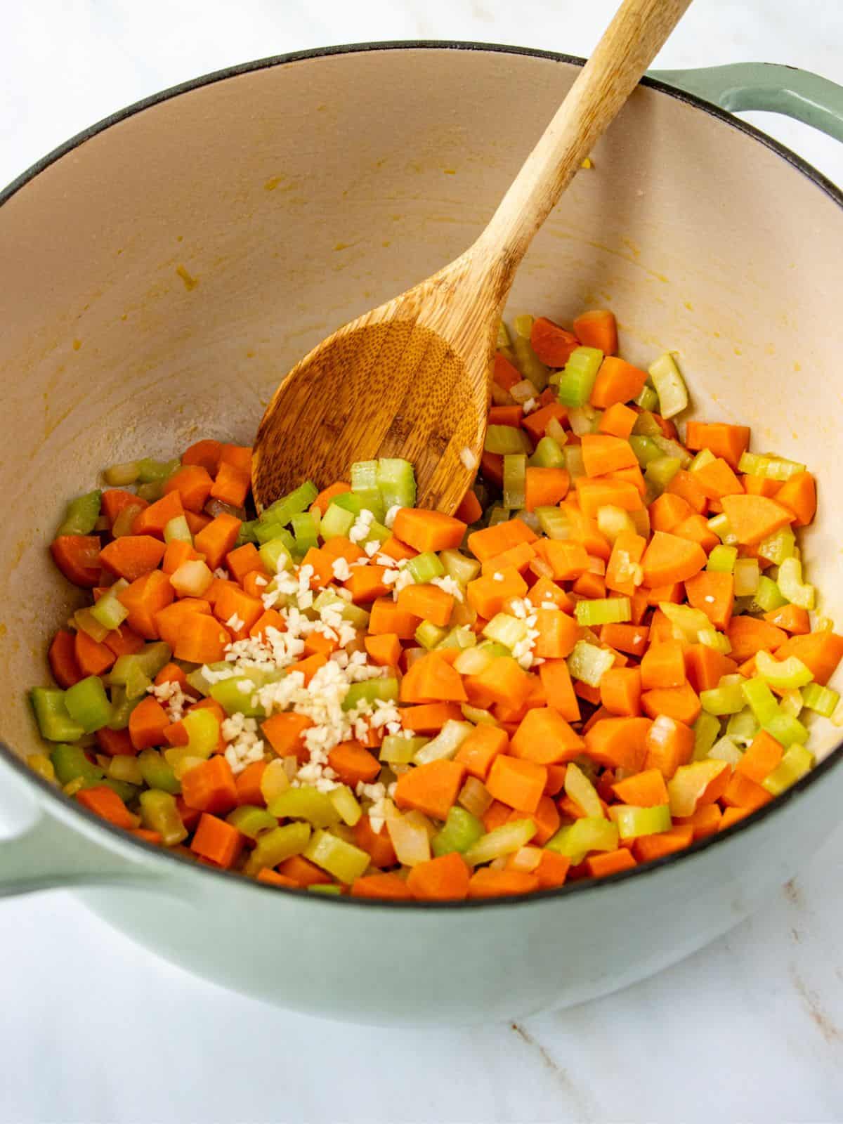 Minced garlic added to pot of diced celery, carrots, and onions.