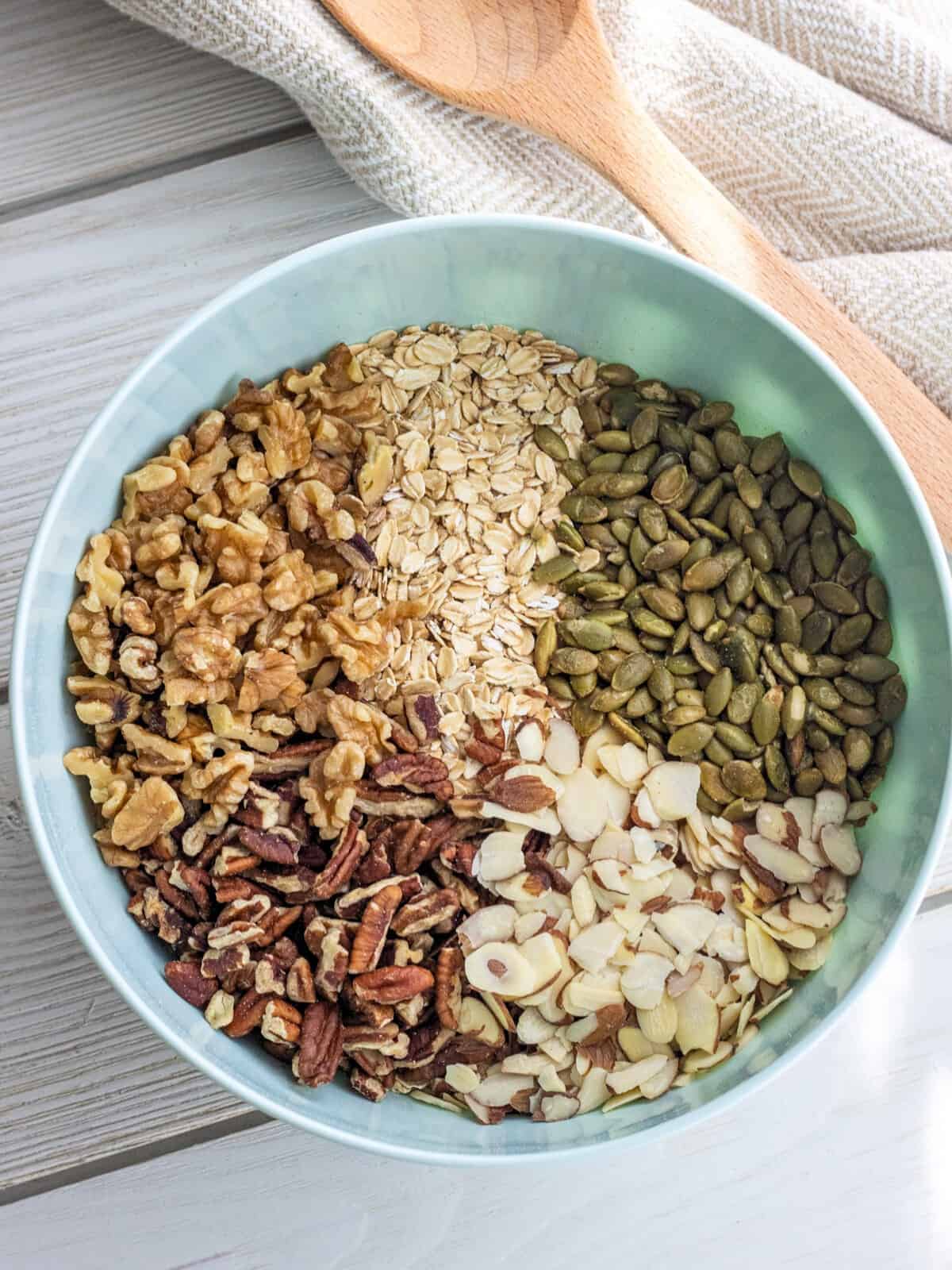 Oats, pumpkin seeds, walnuts, pecans, and almonds in a bowl.