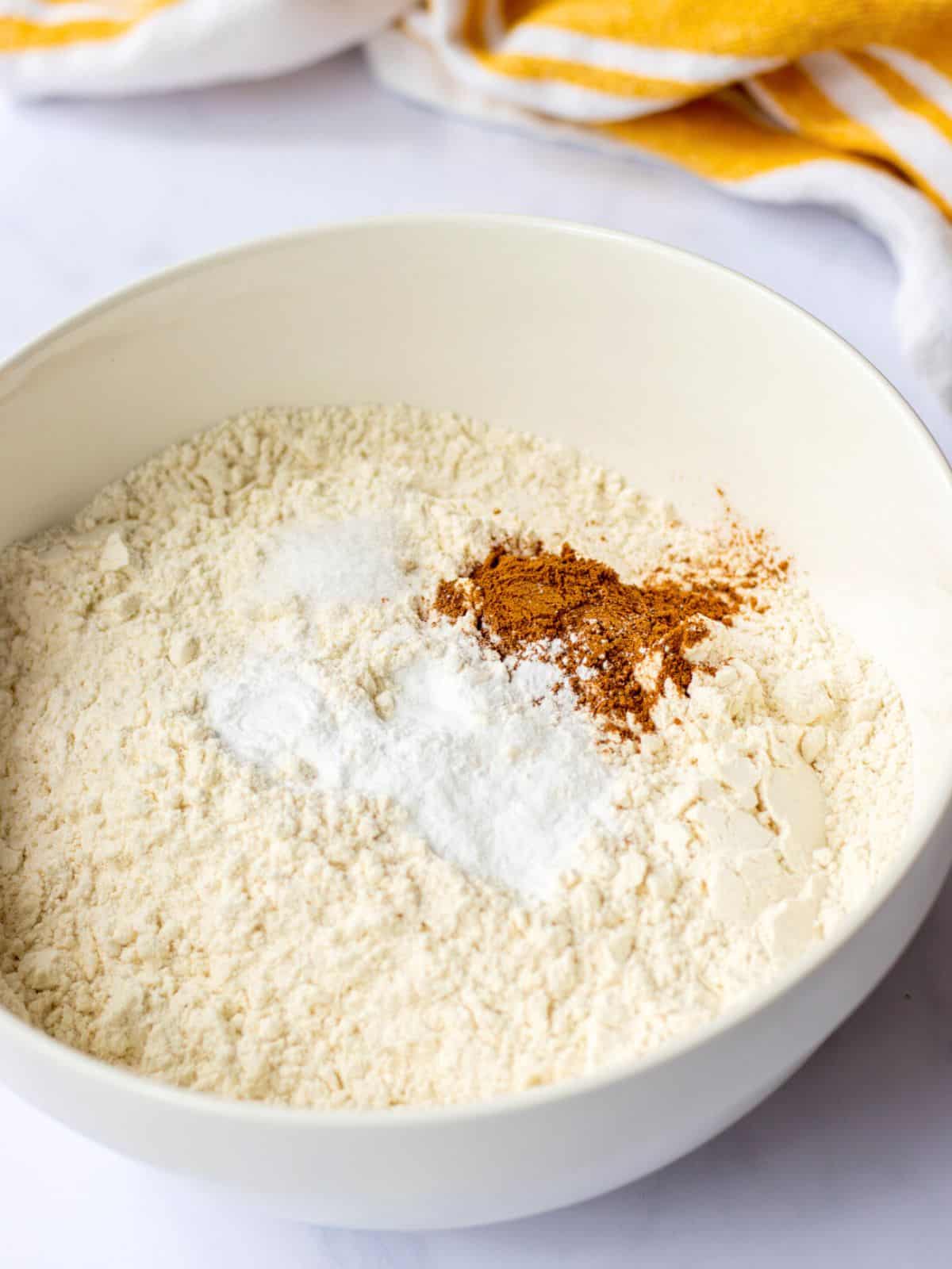 Flour, baking soda, baking powder, cinnamon, and salt in a bowl.