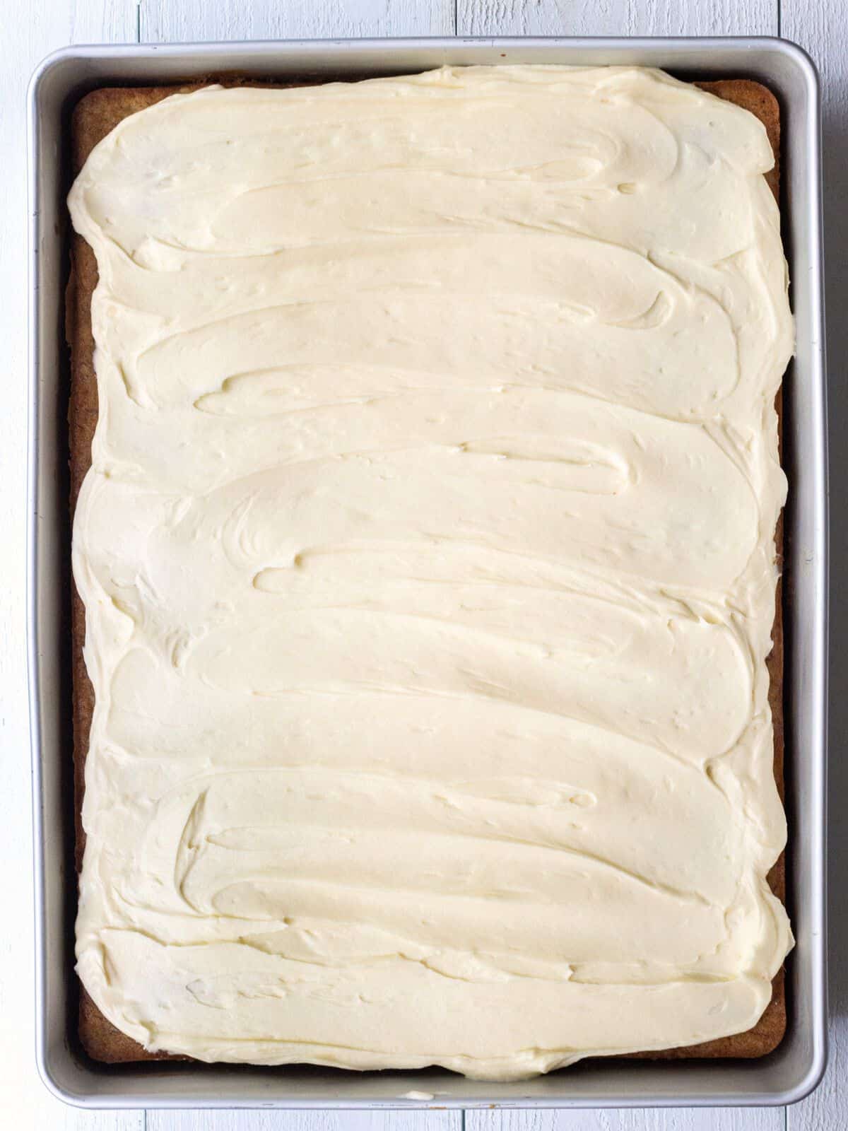 Banana cake topped with frosting in a baking dish.