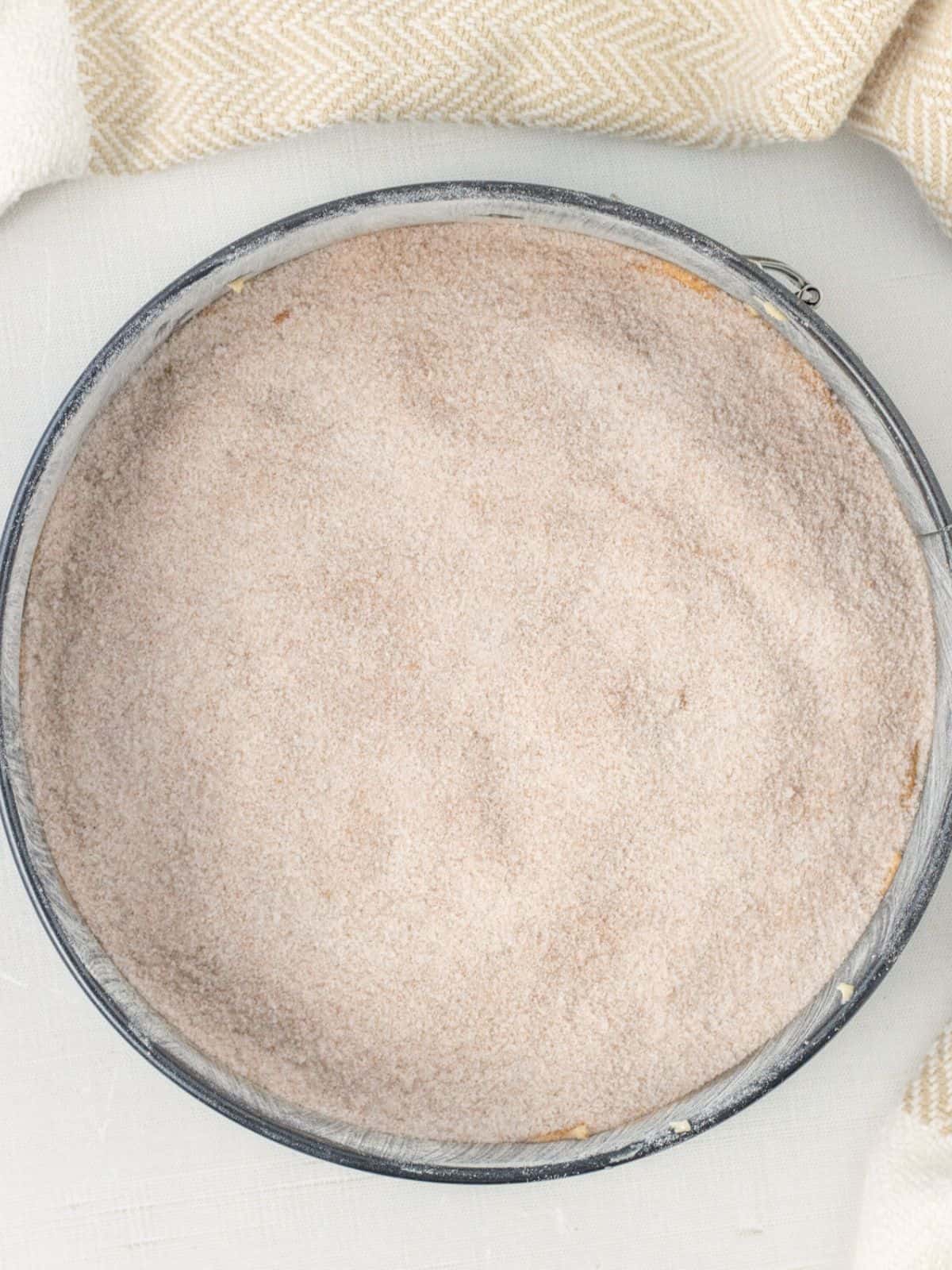 Cinnamon sugar layer added to cake in a springform pan.
