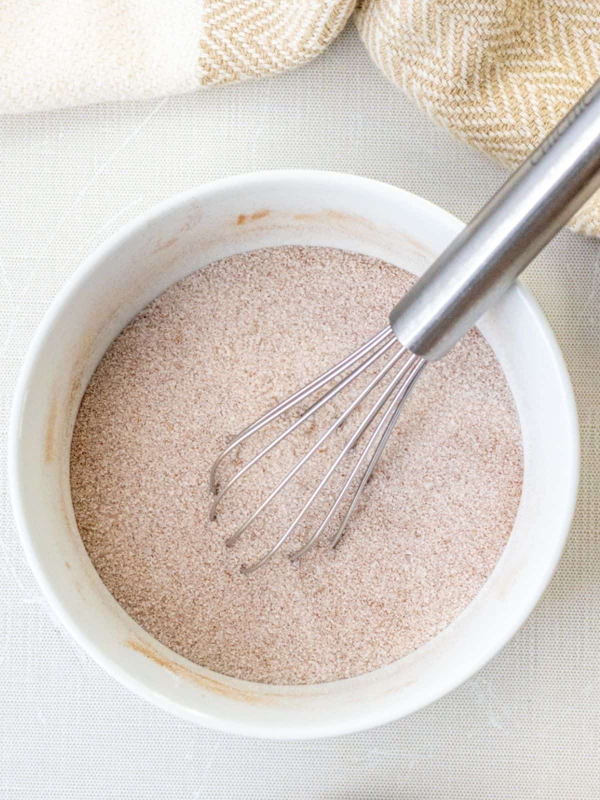 Cinnamon sugar mixture in a bowl with a whisk.