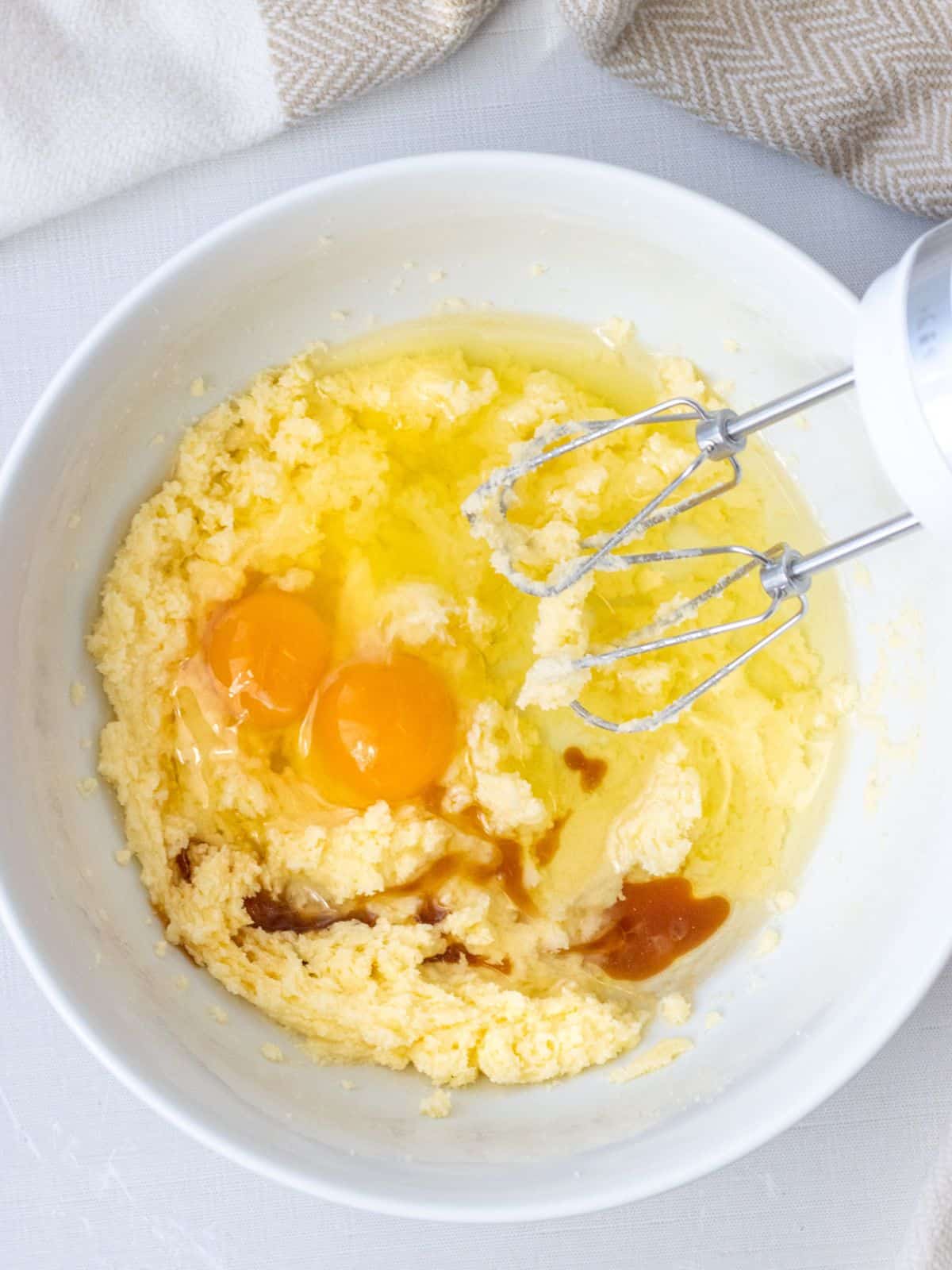 Creamed butter and sugar in a bowl with two eggs, oil, and vanilla extract.