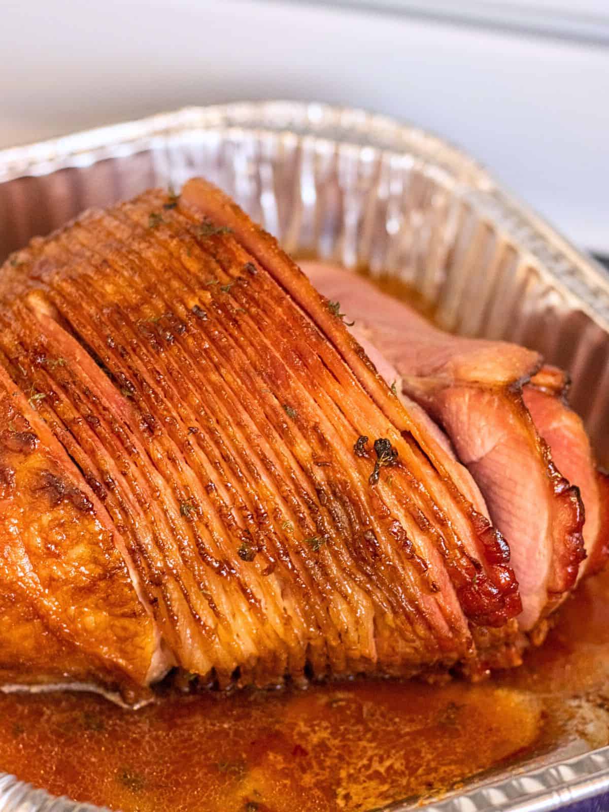 Roasted honey glaze spiral ham in a foil tin.