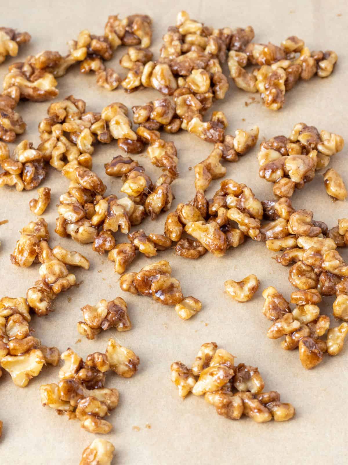 Candied walnuts spread out on parchment paper.