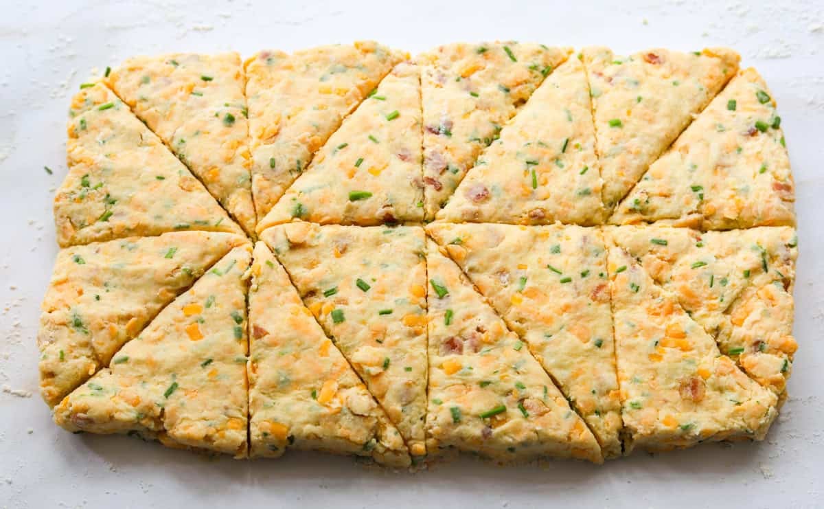 Bacon cheddar chive scone dough cut into triangles.