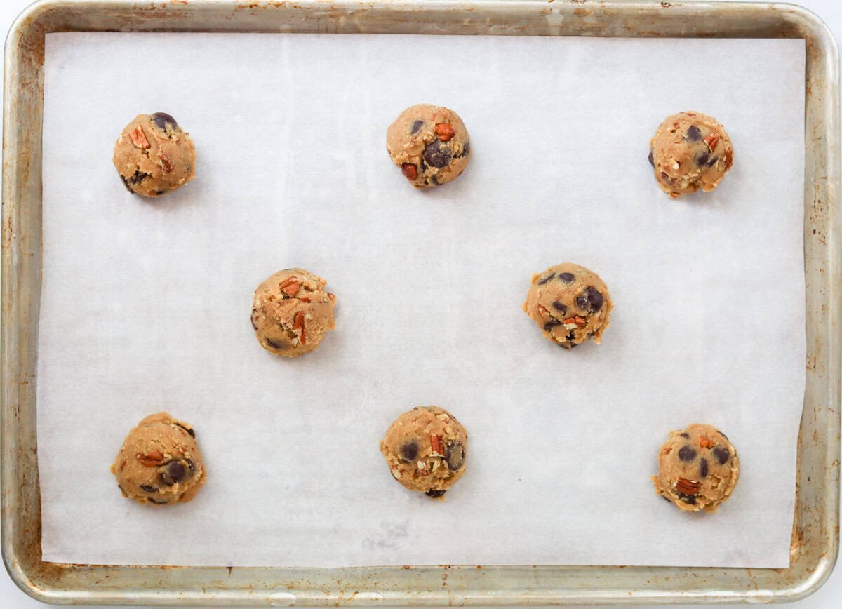 Cookie dough balls on a parchment-lined baking sheet.